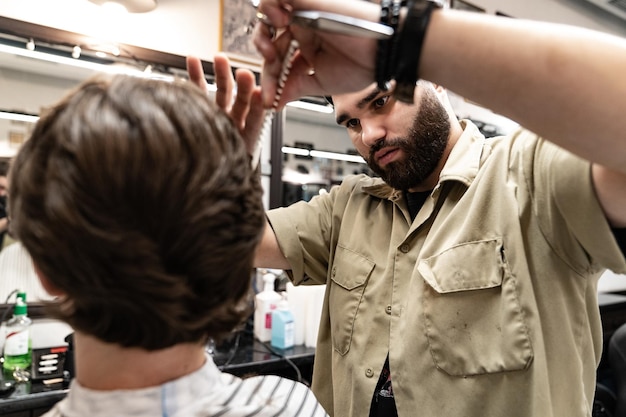 Il cliente riceve un taglio di capelli in un barbiere. Cura dei capelli da uomo. Taglio di capelli con le forbici