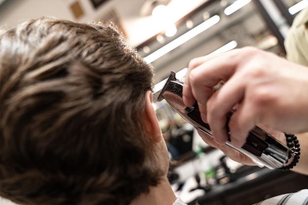 Il cliente riceve un taglio di capelli in un barbiere. Cura dei capelli da uomo. Taglio di capelli con le forbici