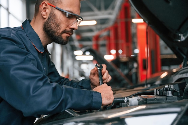 Il cofano è aperto e il riparatore di auto è nel garage con l'automobile