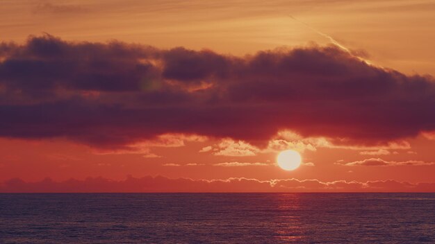 Il colore della luce solare nel cielo che si riflette nell'acqua del mare i toni arancione e rosso si riflettono nell'oceano