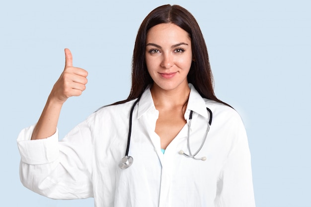 Il colpo orizzontale di medico femminile felice tiene gli aumenti del pollice