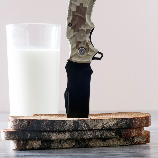 Il coltello è incastrato in pezzi di pane con accanto un bicchiere di latte