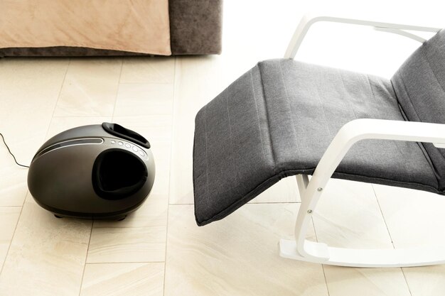 Il comodo massaggiatore elettrico per i piedi si trova vicino alla sedia a dondolo a casa. Massaggio rilassante ai piedi