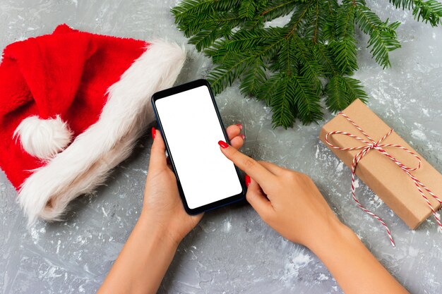 Il compratore femminile fa l'ordine allo schermo dello smartphone con lo spazio della copia. Saldi vacanze invernali. Shopping online di Natale