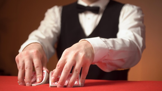 Il concessionario del casinò mescola le carte sulle mani del tavolo rosso da vicino