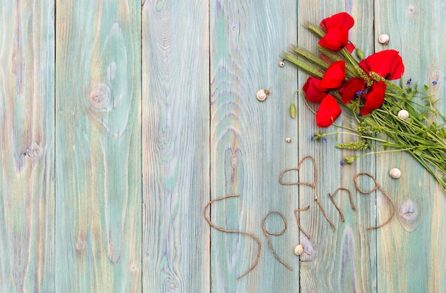 Il concetto che amo la primavera Un bouquet di papaveri primaverili e la parola primavera su un primo piano di fetta di legno