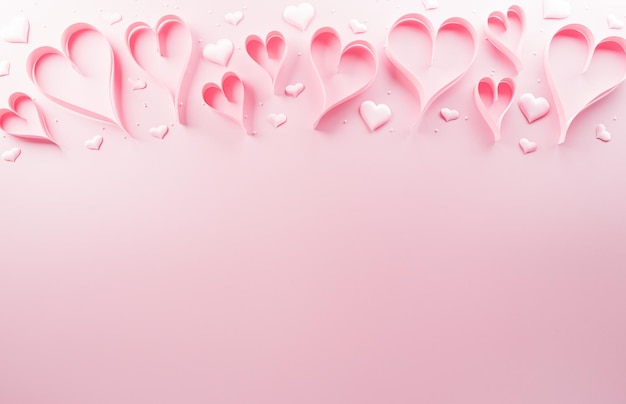 Il concetto del giorno dell'amore e di San Valentino fatto di cuori di carta rosa su sfondo pastello