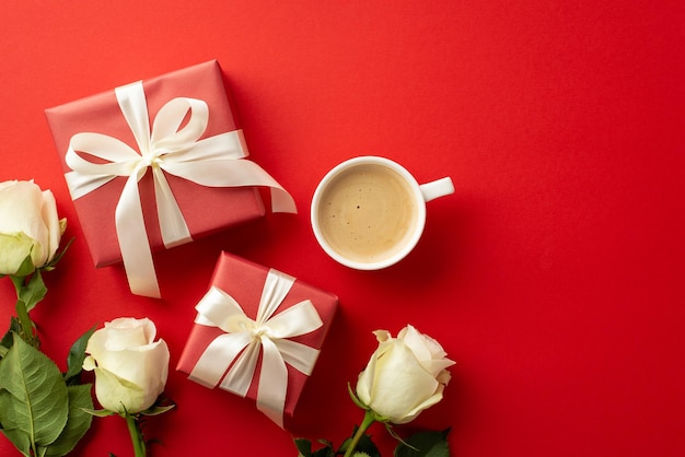 Il concetto del giorno di San Valentino Top view foto di scatole regalo con fiocchi di nastro rose bianche e una tazza di caffè fresco su uno sfondo rosso isolato
