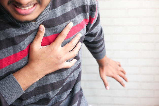 il concetto di attacco di cuore, l'uomo che ha dolore al cuore e che tiene il petto con la mano