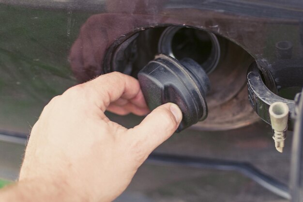 Il concetto di benzina per un'auto La mano è il tappo di avvolgimento del serbatoio del gas