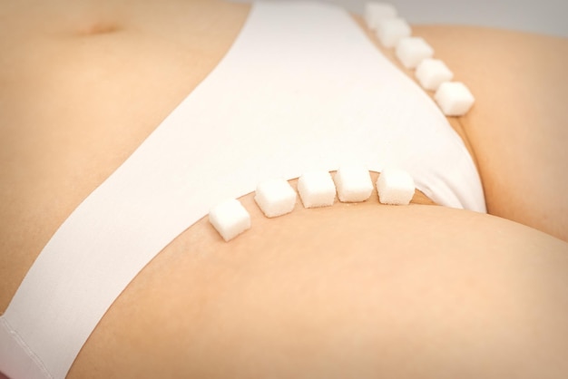 Il concetto di ceretta epilazione e igiene intima Cubetti di zucchero sdraiati in fila sulla zona bikini di una giovane donna bianca da vicino