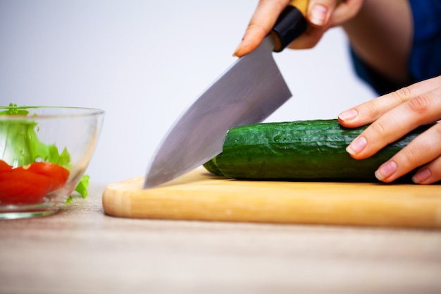 Il concetto di cibo sano, la donna taglia gli ortaggi freschi per insalata