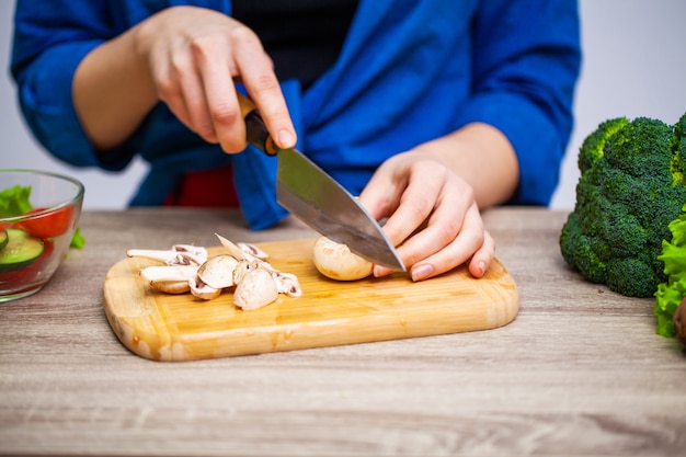 Il concetto di cibo sano, la donna taglia gli ortaggi freschi per insalata