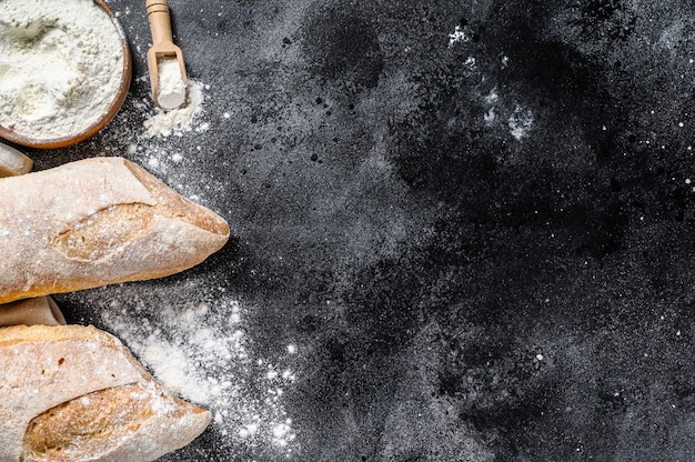 Il concetto di cucinare il pane fatto in casa. Baguette francese. sfondo nero. vista dall'alto. Copia spazio