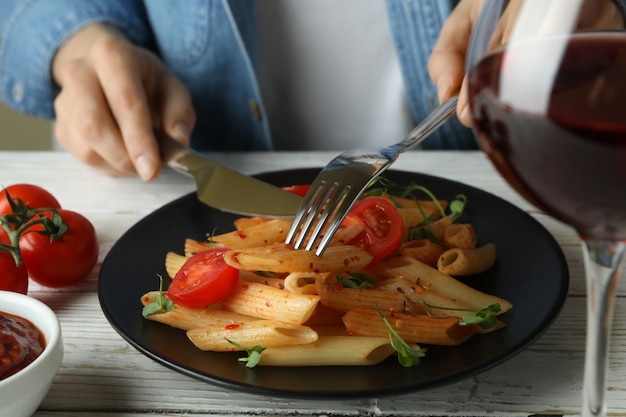 Il concetto di gustoso mangiare con la donna mangia la pasta con salsa di pomodoro