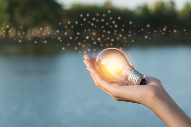 Il concetto di innovazione ed energia della mano tiene una lampadina