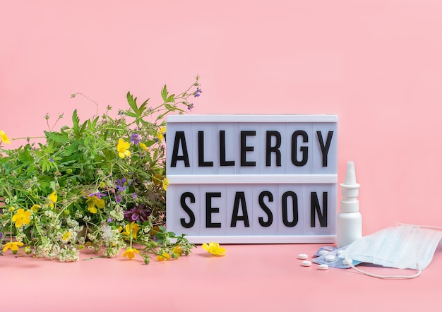 Il concetto di lotta alla prevenzione delle allergie stagionali Le pillole per la maschera medica di fiori freschi fanno cadere la medicina sullo sfondo rosa