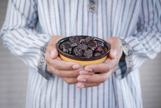 Il concetto di mano del ramadan con una ciotola di frutti di dattero