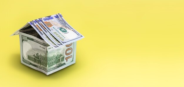 Il concetto di mutuo e locazione immobiliare e immobiliare. Prestito di credito ipotecario. Casa fatta di banconote da un dollaro su sfondo giallo.