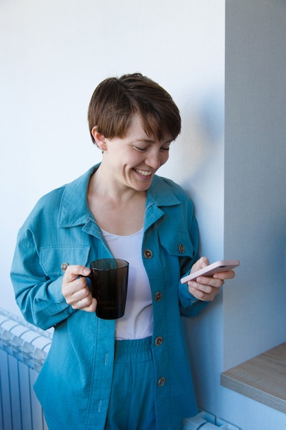 Il concetto di occupazione, interviste, pubblicità della tecnologia digitale - donna che beve caffè e parla al telefono. La donna sorridente con la tazza fa una chiamata. Mattina della ragazza