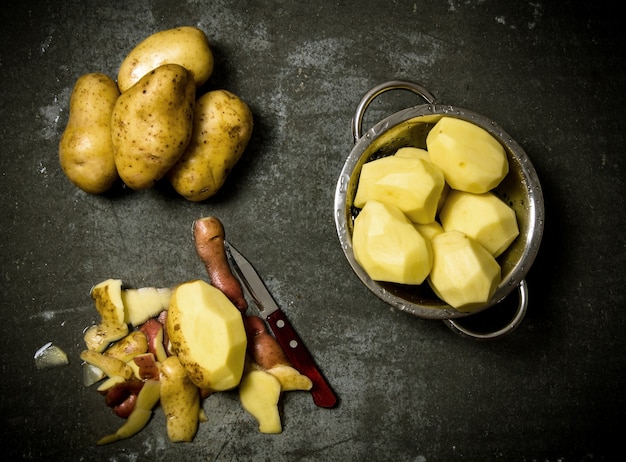 Il concetto di patate sbucciate bagnate sul tavolo di pietra.