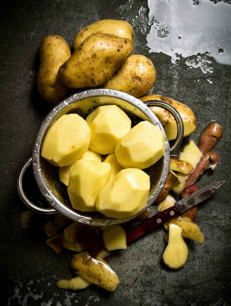 Il concetto di patate sbucciate bagnate sul tavolo di pietra