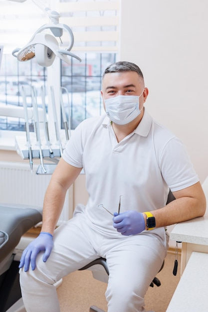 Il concetto di professione medica odontoiatria e medicina un dentista sorridente di mezza età sullo sfondo di uno studio medico Il dentista è nel suo studio dentistico