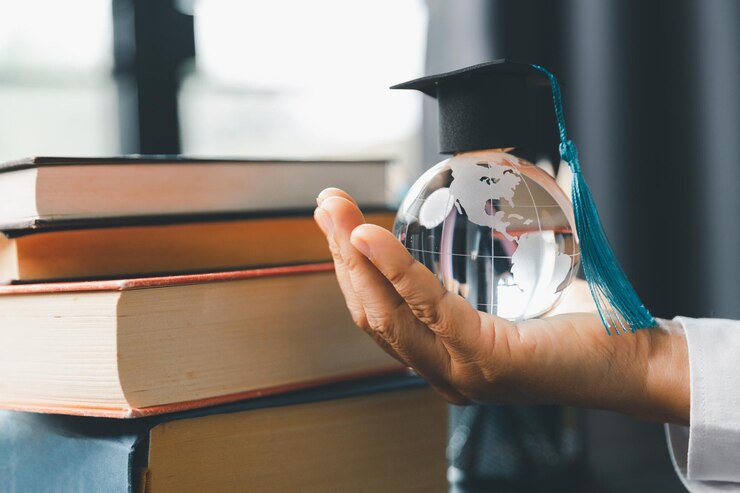 Foto il concetto di programma di studi universitari all'estero cappuccio di laurea nero su una mappa del globo e libri raffigura la conoscenza può essere imparata online ovunque e ovunque anche nelle università o nei campus di tutto il mondo
