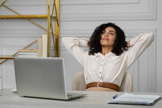 Il concetto di relax in ufficio una donna indiana con i capelli neri ricci si allunga con le mani