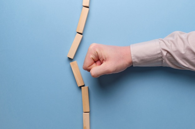 Il concetto di rottura degli stereotipi. La mano tiene blocchi di legno su uno spazio blu.