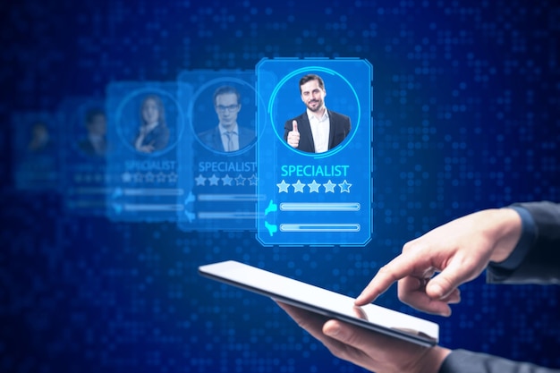 Il concetto di servizio di ricerca online dell'applicazione di reclutamento online con la mano dell'uomo d'affari che punta al telefono cellulare con le carte del profilo virtuale contengono valutazioni e foto del candidato su sfondo blu sfocato