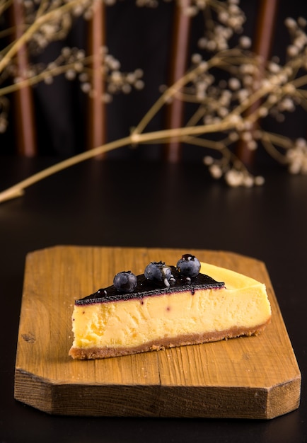 Il concetto di torte. Cheesecake con mirtilli e caramello su fondo nero