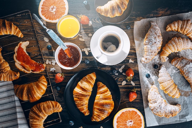 Il concetto di una colazione ampia e varia diversi croissant e marmellate caffè e succo di amelsin pompelmo e fragole sul tavolo vista dall'alto