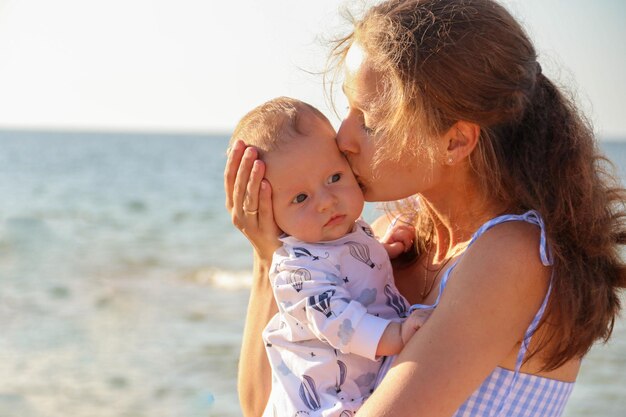 Il concetto di una famiglia armoniosa felice e di una maternità felice all'aperto La madre abbraccia il suo bambino contro