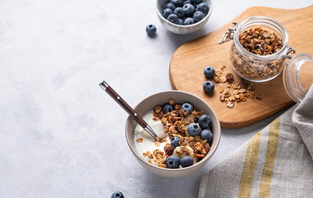 Il concetto di una sana colazione a base di muesli allo yogurt e mirtilli freschi su sfondo chiaro Dieta fatta in casa e alimenti proteici