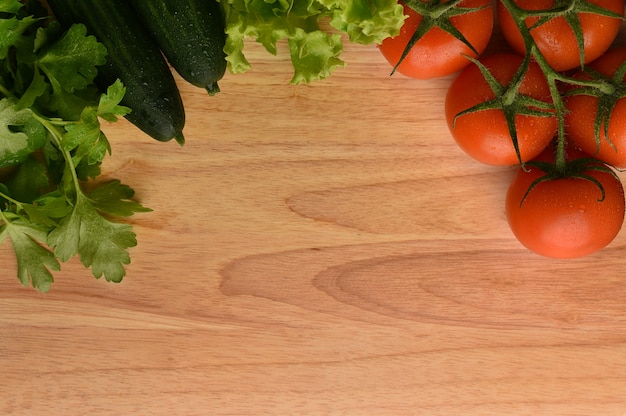 Il confine della verdura fresca ha messo su un fondo di legno naturale. Mockup per menu o ricetta. Verdure con gocce d'acqua.