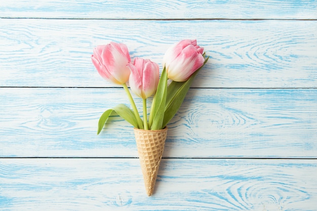Il cono di cialda si trova su uno sfondo vintage in legno. Tulipani, fiori di primavera