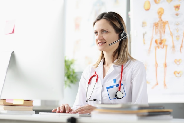 Il consulente medico femminile sorridente in cuffie sta fornendo assistenza medica a distanza