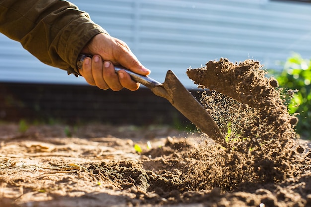 Il contadino scava il terreno nell'orto Preparazione del terreno per piantare ortaggi Concetto di giardinaggio Lavori agricoli nella piantagione