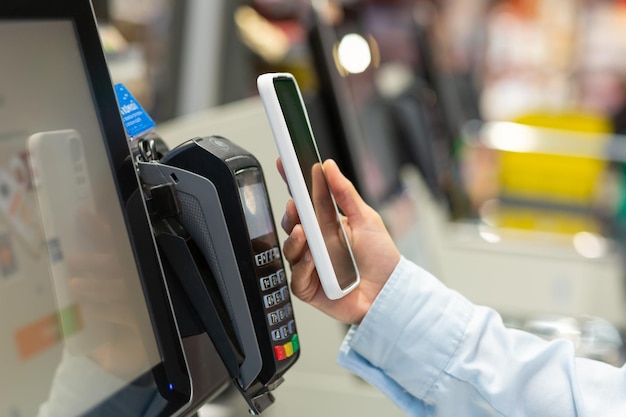 Il contatore della donna del primo piano acquista la mano femminile dello smartphone del supermercato di pagamento elettronico con un telefono cellulare