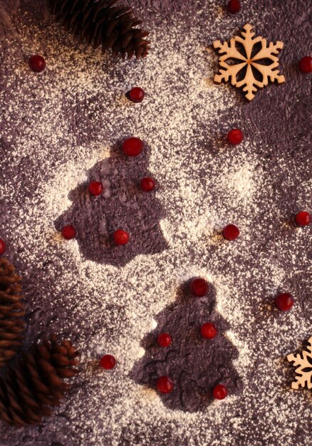Il contorno dell'albero di Natale con zucchero a velo di bacche rosse su sfondo scuro