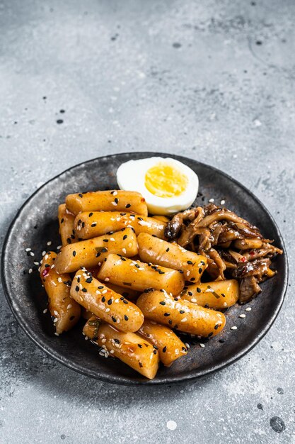 Il coreano Tteokbokki Topokki torta di riso fritto stick in salsa calda e piccante Sfondo grigio Vista dall'alto