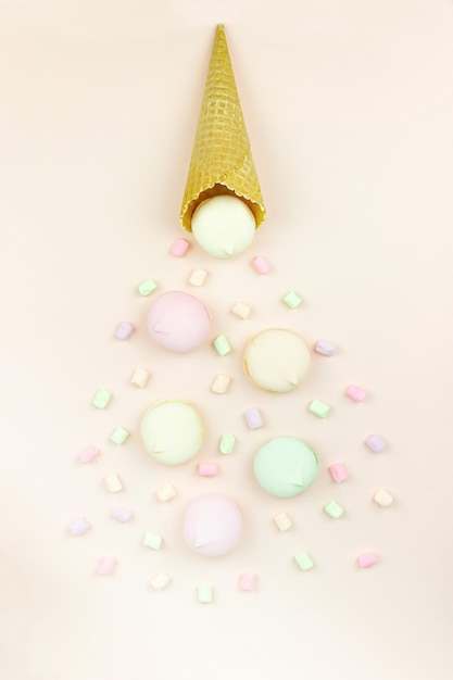 Il corno di wafer si alza e il marshmallow sembra amaretti su uno sfondo pastello, vista dall'alto, disposizione piatta, tendenza minimalista, concetto di dessert dolce