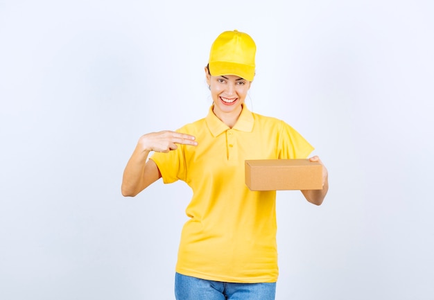 Il corriere femminile in uniforme gialla ha consegnato un pacco di cartone all'indirizzo giusto.