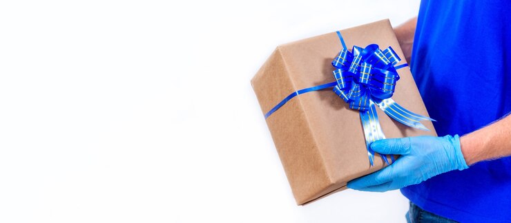 Il corriere in guanti blu tiene il contenitore di regalo