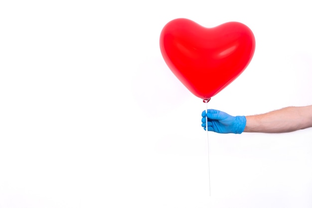 Il corriere in guanti protettivi tiene un palloncino rosso a forma di cuore per San Valentino