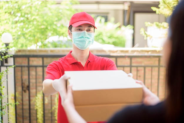 Il corriere in maschera protettiva e guanti consegna cibo in scatola durante lo scoppio del virus. Consegna a domicilio sicura.