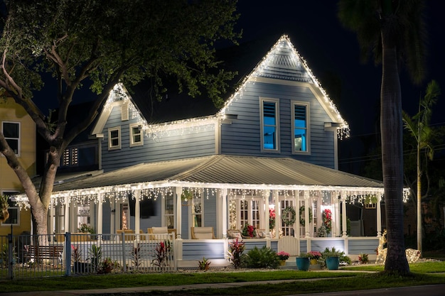 Il cortile anteriore della casa con un grande portico illuminato brillantemente con decorazioni natalizie Decorazione esterna della casa di famiglia in Florida per le vacanze invernali