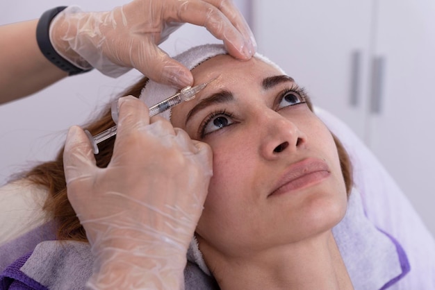 Il cosmetologo esegue iniezioni di filler antirughe rigeneranti con filler di acido ialuronico in un viso di donna Cosmetologia estetica femminile in un salone di bellezza