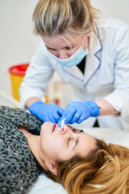 Il cosmetologo medico fa la procedura di aumento delle labbra di una bella donna in un salone di bellezza